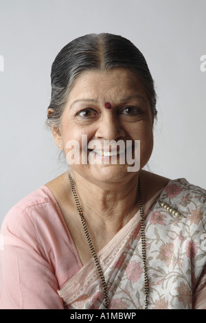 Indian senior citizen con puntino sulla fronte in sari guardando felice della fotocamera Foto Stock