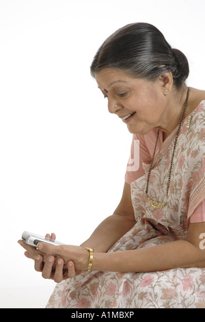 Indian senior citizen puntino sulla fronte in sari vedendo SMS sul cellulare Foto Stock