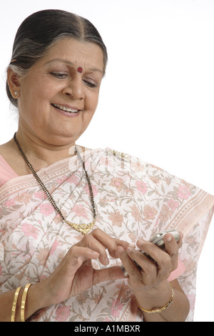 Indian senior citizen puntino sulla fronte in sari vedendo SMS sul cellulare Foto Stock