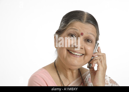 Indian senior citizen puntino sulla fronte in sari parlando al cellulare Foto Stock