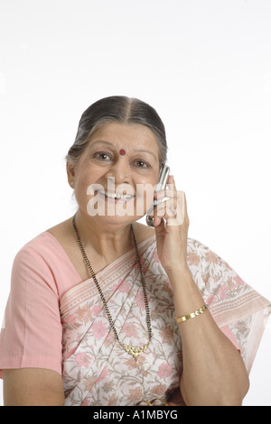 Indian senior citizen puntino sulla fronte in sari parlando al cellulare Foto Stock