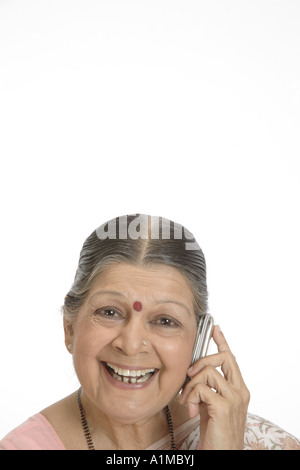 Indian senior citizen puntino sulla fronte in sari parlando al cellulare Foto Stock