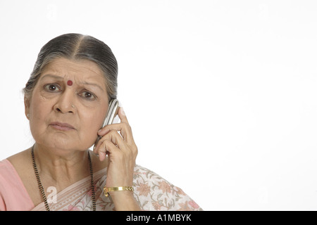 Indian senior citizen puntino sulla fronte in sari parlando al cellulare Foto Stock