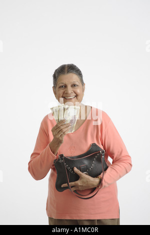 Indian senior citizen rimuovendo i soldi dalla borsa Foto Stock