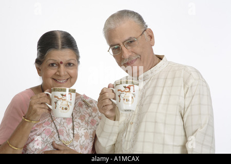 Indian senior citizen giovane bere il tè su sfondo bianco Foto Stock