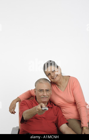 Felice Indian senior citizen giovane premendo remote su sfondo bianco Foto Stock