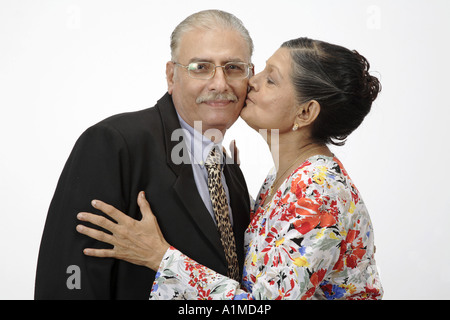 Indiano amorevole senior citizen giovane moglie baciare mio marito sulla guancia Foto Stock