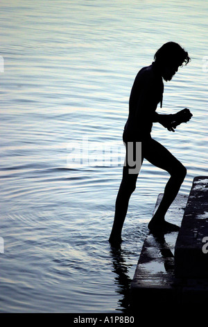 Un uomo è prendere un bagno nel fiume santo del Gange a Varanasi in India Foto Stock