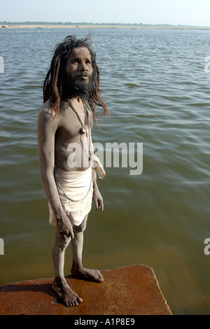 Un sadhu sorge sulla riva del fiume sacro Gange a Varanasi in India del nord Foto Stock