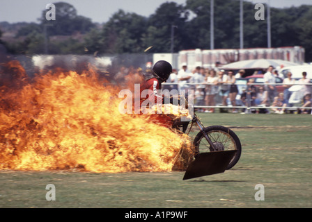 Acrobatico pilota in moto da vicino attraverso un tunnel bruciato realizzato con balle di paglia imbevute di benzina nell'arena con spettatori al Fete Essex England UK Foto Stock