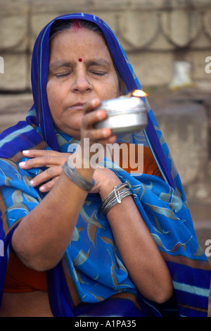 Una donna sta eseguendo un rituale religioso sulle rive del Gange a Varanasi in India del nord Foto Stock