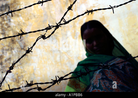 Una donna indiana si siede dietro una staccionata di filo spinato a Nuova Delhi in India Foto Stock