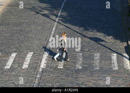 Due donne che attraversano una strada acciottolata in una giornata di sole a Kiev. Foto Stock