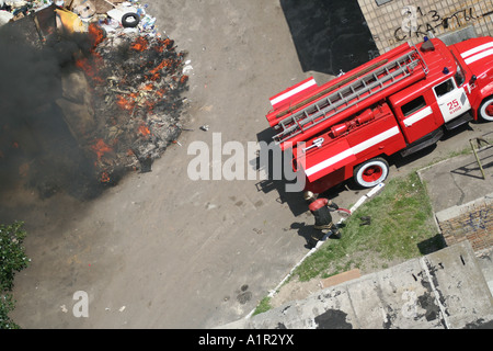 Vigili del fuoco che spengono un incendio a Kiev con un camion antincendio in loco, fumo e fiamme visibili. Foto Stock