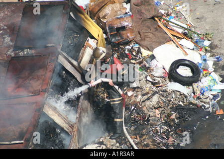 Vigile del fuoco che brucia fiamme tra detriti e fumo a Kiev, Ucraina. Foto Stock