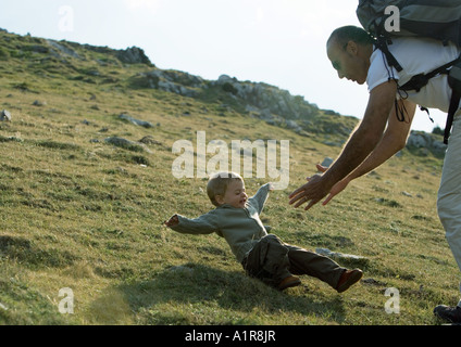 Ragazzo che cadono come padre raggiunge per lui Foto Stock