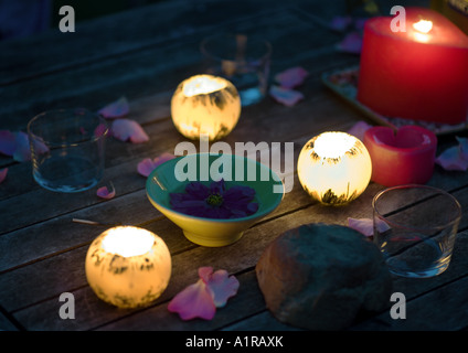 Candele incandescente sulla tavola decorata con petali di rosa e la vasca di contenimento floating flower Foto Stock