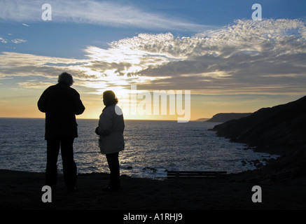 Coppia di anziani e guardare il tramonto sopra la linea costiera di Gower dal punto Langland vicino a Swansea, Wales, Regno Unito. Foto Stock