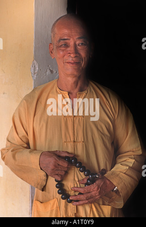 Abate di un monastero vietnamita di Saigon in piedi in una porta e tenendo la preghiera buddista perle Ho Chi Minh City Vietnam Foto Stock