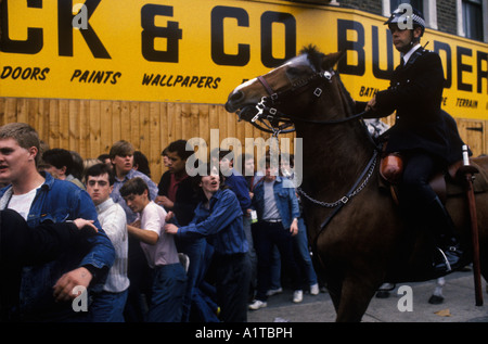 Arsenal contro Chelsea, tifosi di calcio dell'Arsenal dopo un gioco di polizia controllo della folla a cavallo Londra UK. Ragazzo adolescente guardato spaventato. Circa 1985 OMERO SYKES Foto Stock