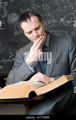 Ritratto insegnante maschio in seduta student desk Foto Stock