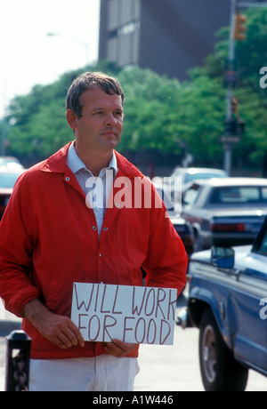 Detroit Michigan un ex benessere destinatario detiene una lettura del segno lavorerà per alimenti come egli sta accanto a una strada trafficata Foto Stock