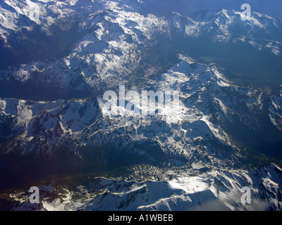 Le Alpi in alto nel cielo formazioni di nubi visto da sopra aloft al di fuori di un finestrino per aerei di volare al di sopra delle Alpi Foto Stock