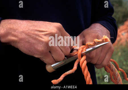 Close up di un fishermans mani che è rammendo corda e net Foto Stock