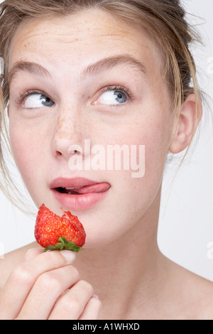 Ritratto di una giovane donna di mangiare una fragola Foto Stock