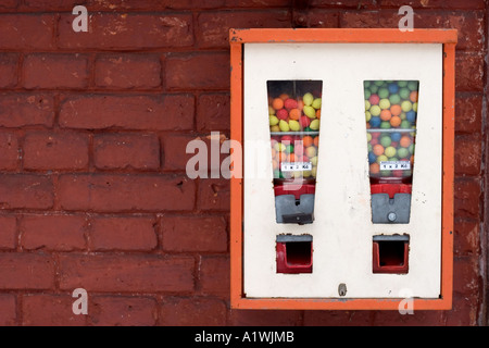 Distributore automatico di chewing gum su un rosso mattone parete di alloggiamento Foto Stock