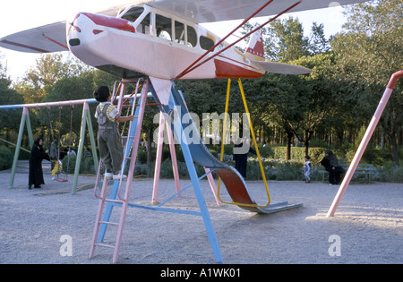 Parco giochi a Teheran in Iran 1999. I bambini giocano su una slitta che ha un piccolo aeroplano come parte di esso Foto Stock