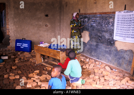 Ruanda KIGALI SCUOLA PRIMARIA .un insegnante dà una lezione rivolta verso la lavagna in un aula distrutta disseminato di mattoni Foto Stock