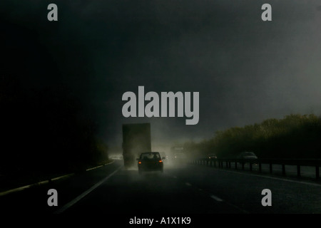 Spray pesanti catturati da sole durante forti piogge provenienti dal camion su autostrada M4 Inghilterra con auto seguente che mostra la luce del freno Foto Stock