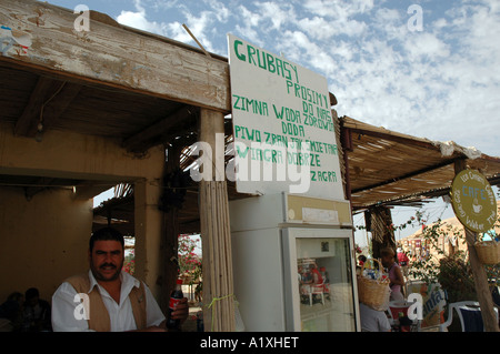 L'uomo la vendita di acqua e bevande in stallo in Chebika oasi nel Atlante Sahariano montagne, Tunisia, segno è in lingua polacca... Foto Stock