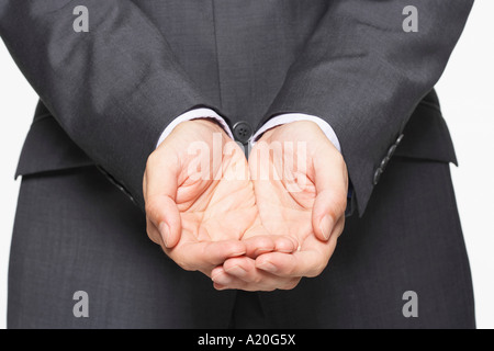 Imprenditore coppettazione le sue mani, close-up su mani, metà sezione Foto Stock
