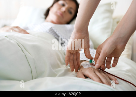 Medico di fissaggio tubo per via endovenosa per mano del paziente, close up delle mani Foto Stock