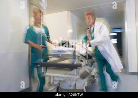 I medici del paziente in esecuzione su barella attraverso il corridoio di ospedale, sfocatura del movimento Foto Stock