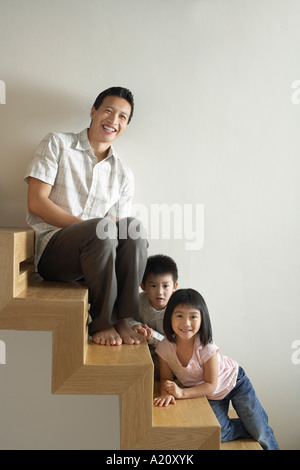 Padre seduto con i bambini sulla scala di legno Foto Stock
