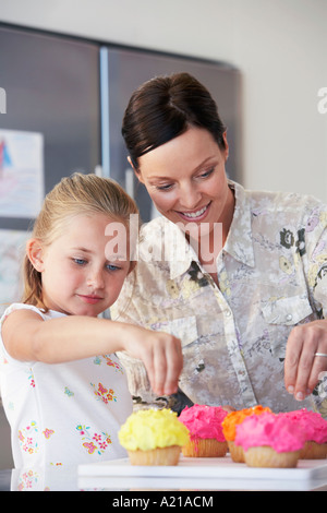 Madre e figlia come decorare le tortine in cucina Foto Stock
