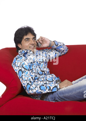VDA200167 South Asian Indian uomo seduto sul divano a parlare sul cellulare i jeans e maglietta MR 701 Foto Stock