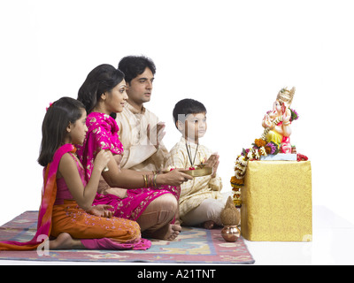 South Asian famiglia indiana con padre madre figlio e figlia seduta la preghiera al Signore Ganesha indossando vestiti tradizionali kurta Foto Stock