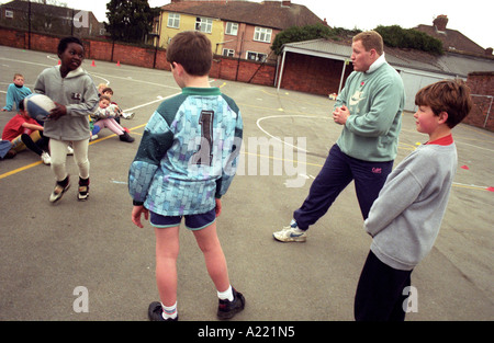 Insegnante di rugby con gli allievi nel parco giochi Foto Stock