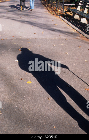 Ombra di un uomo anziano con una canna che cammina solo nel parco. Foto Stock