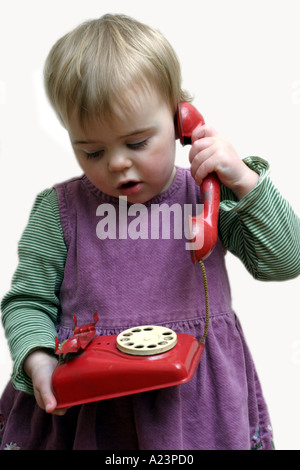 18 mese vecchia ragazza parlando sul vecchio telefono giocattolo Foto Stock
