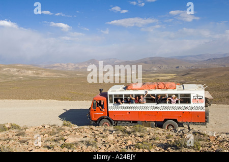 Un overland adventure holiday carrello viaggia attraverso la campagna del Perù con tutti i passeggeri sventolare dalle finestre. Foto Stock