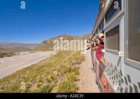 Un overland adventure holiday carrello che viaggia lungo una strada sterrata in Perù con i passeggeri appoggiata dalla finestra sventolando. Foto Stock