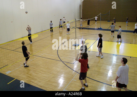 Agli studenti di giocare a pallavolo in palestra classe Foto Stock