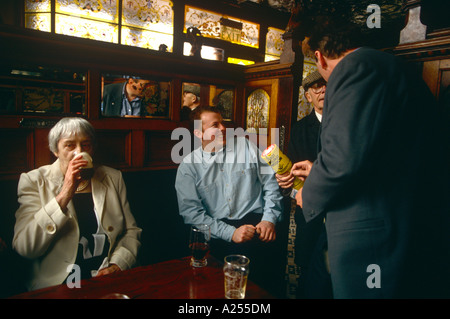 I bevitori di Belfast's Crown Bar in Great Victoria Street godetevi una pinta di birra e parlare con un lavoratore di carità. Foto Stock