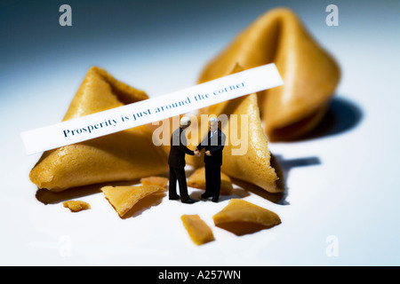 Due imprenditore in miniatura nella parte anteriore del Fortune cookie con la lettura del messaggio della prosperità è proprio dietro l'angolo Foto Stock