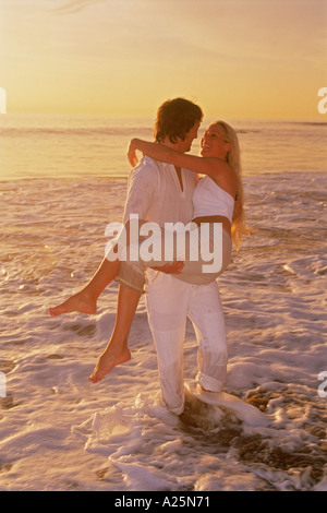 Giovane godendo momenti romantici in ondulazioni lungo la costa della California al tramonto Foto Stock